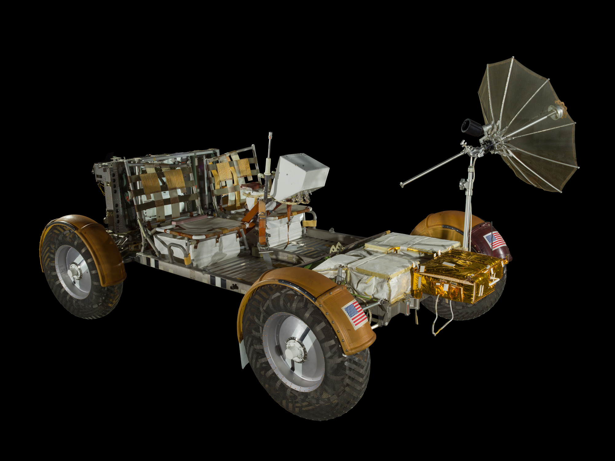 Open lightweight four-wheel lunar rover with wire-mesh wheels, two webbed seats, hand controller, fenders, and dish antenna.