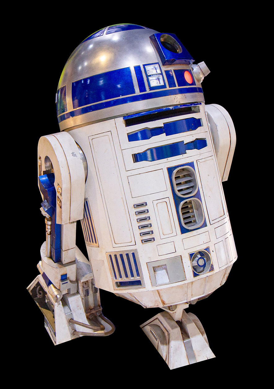 A short blue, white, and silver cylindrical R2-D2 replica with a domed head, three legs, and compartments for tools and sensors.