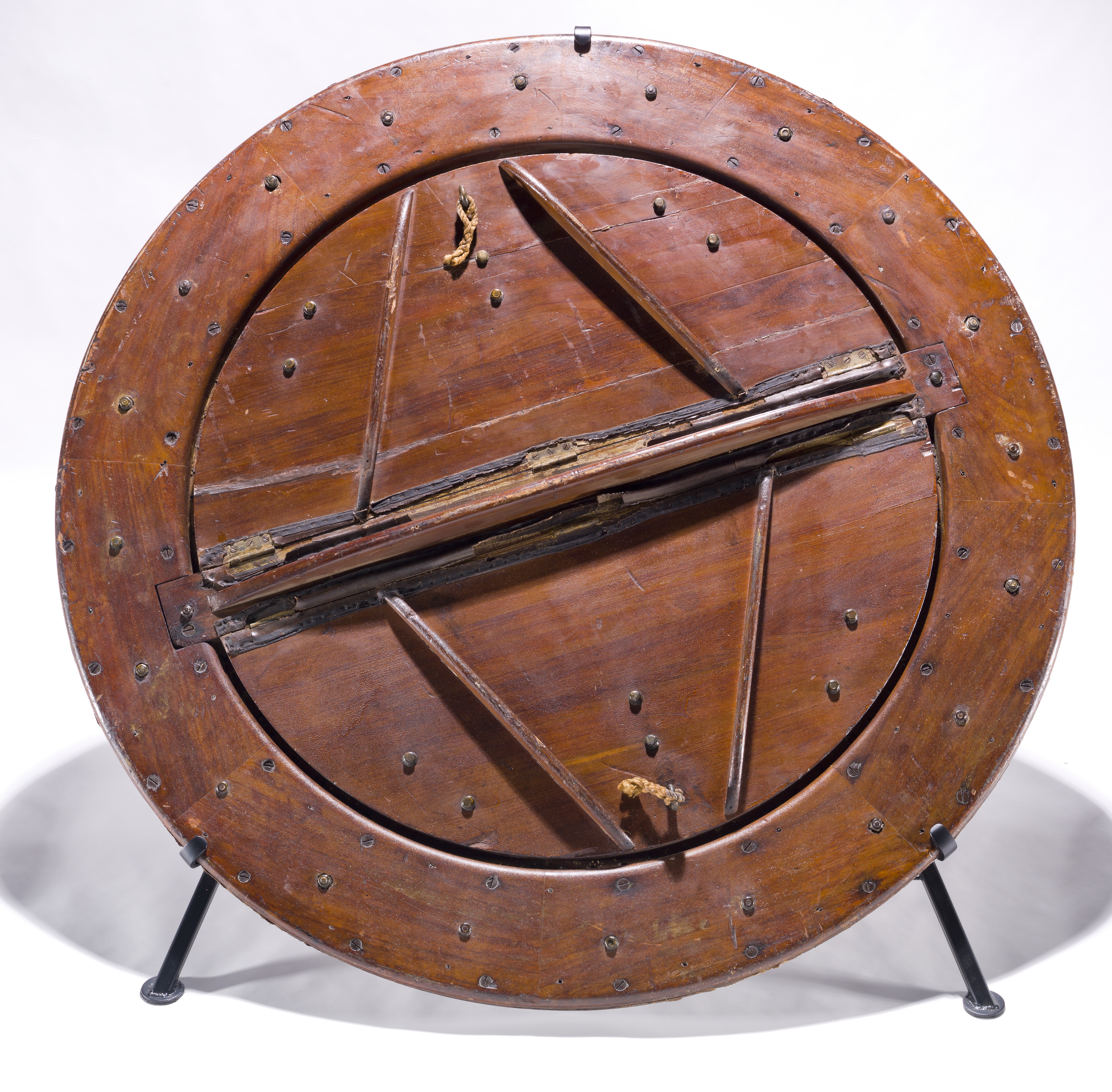 A large circular wooden balloon valve made of radial planks and reinforced supports, with an aged, cracked surface.