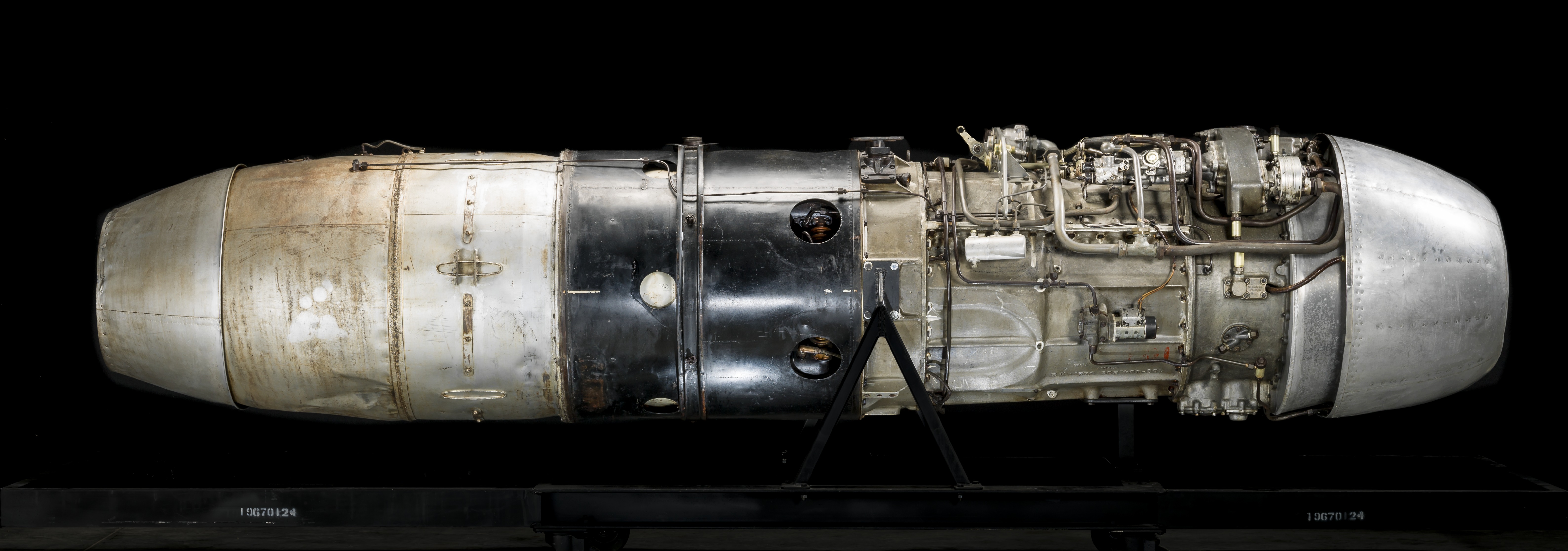A long cylindrical axial-flow jet engine with exposed metallic surfaces, compressor stages, pipes, and mechanical components.