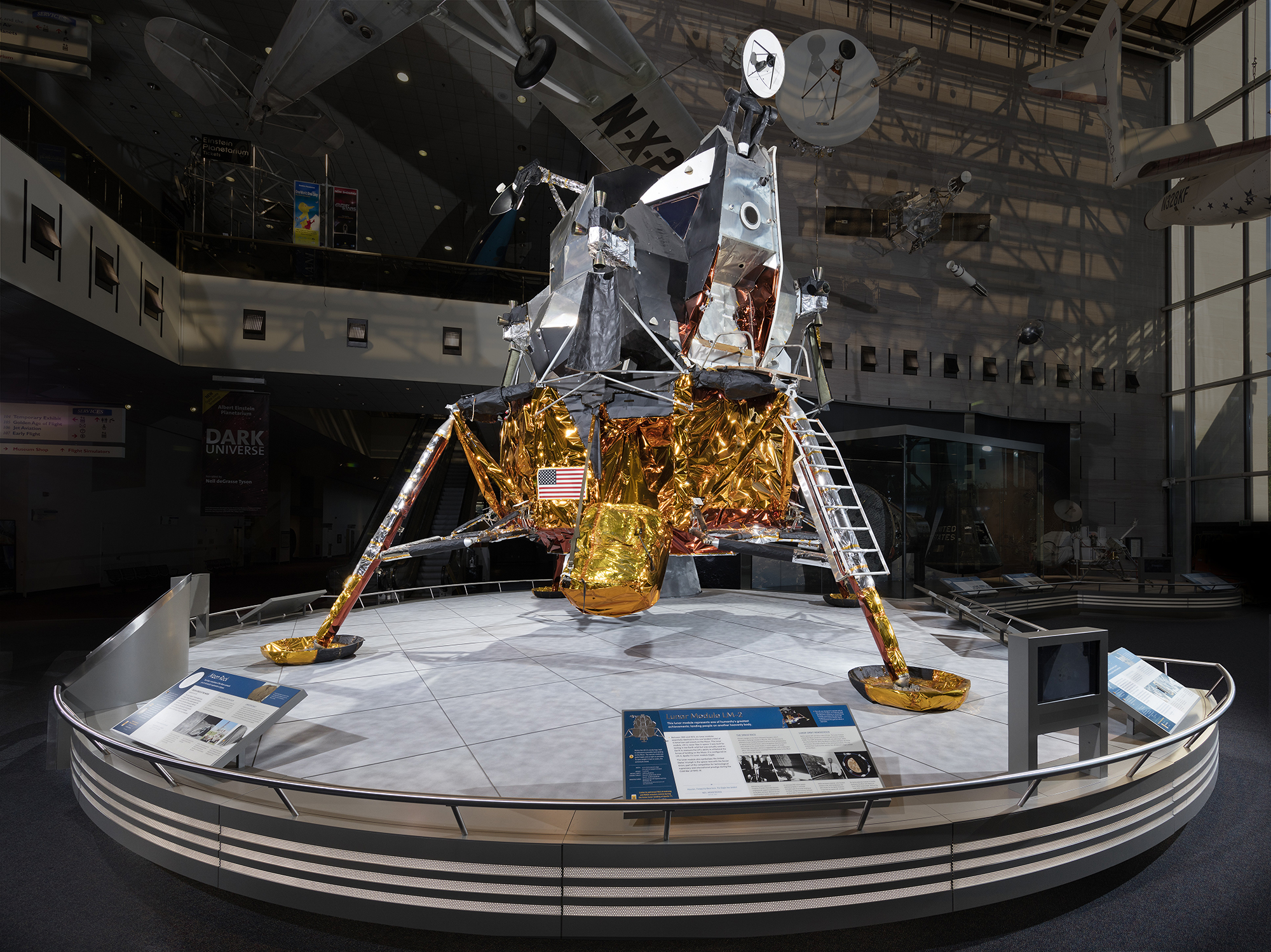A two-stage lunar module with four gold-wrapped landing legs and footpads beneath an angular silver ascent stage with windows, hatch, ladder, dish antenna, and thrusters.