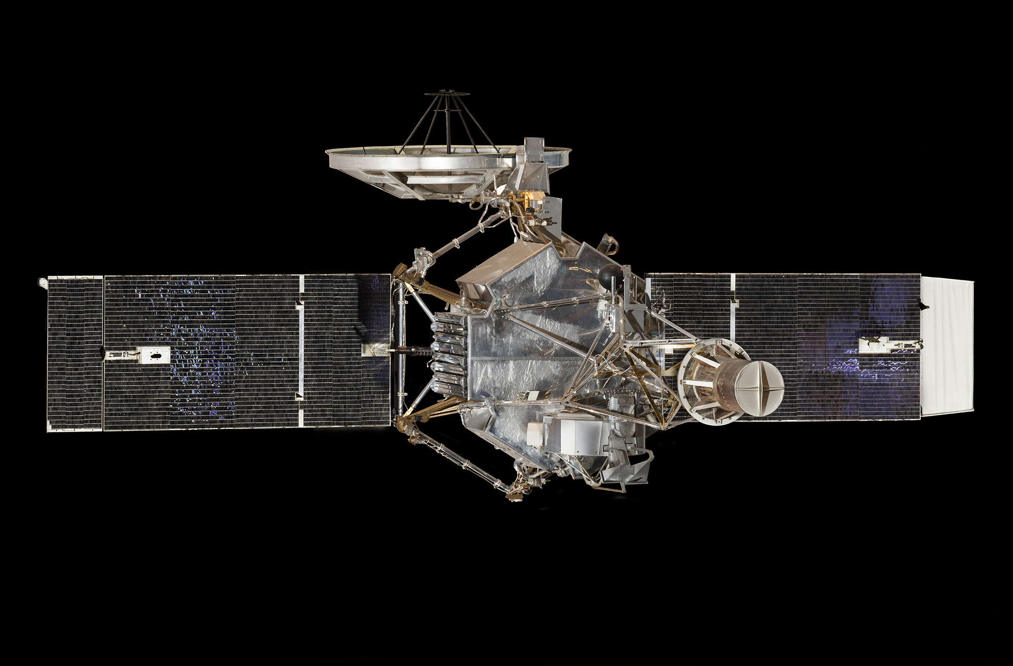 A silver hexagonal spacecraft with solar panels, a circular high-gain antenna, and instruments mounted around its body.