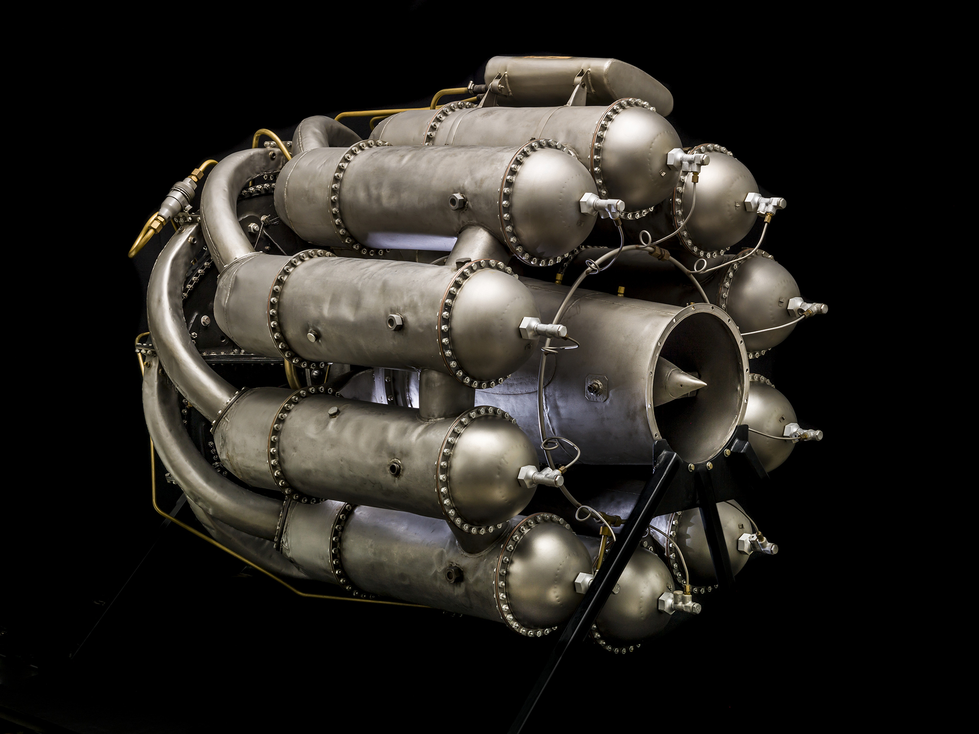 A compact silver centrifugal-flow turbojet with a central compressor case, multiple combustion chambers, pipes, and an exhaust section.
