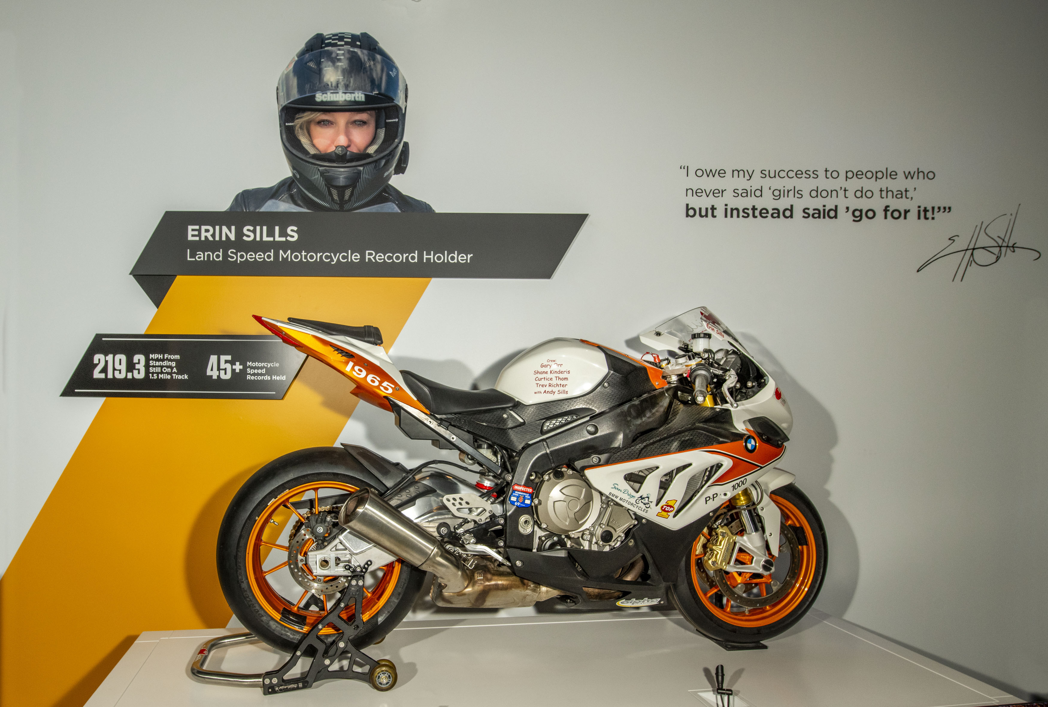 Modern white, gray, and orange racing motorcycle with black seat, black tires, and orange wheel rims.