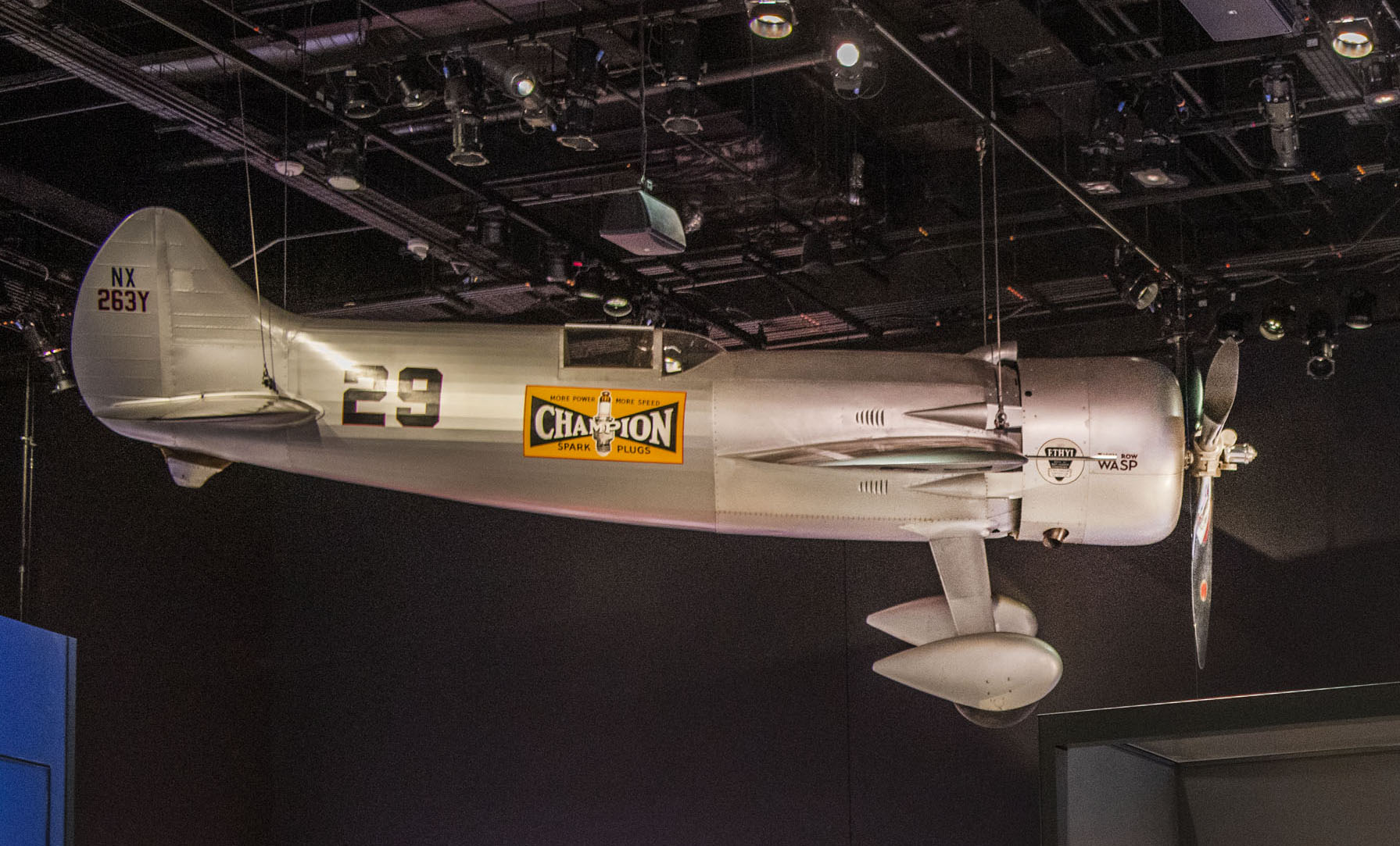 Silver single-seat racing aircraft with broad low wings, a covered cockpit, streamlined landing gear, and number 29 markings.