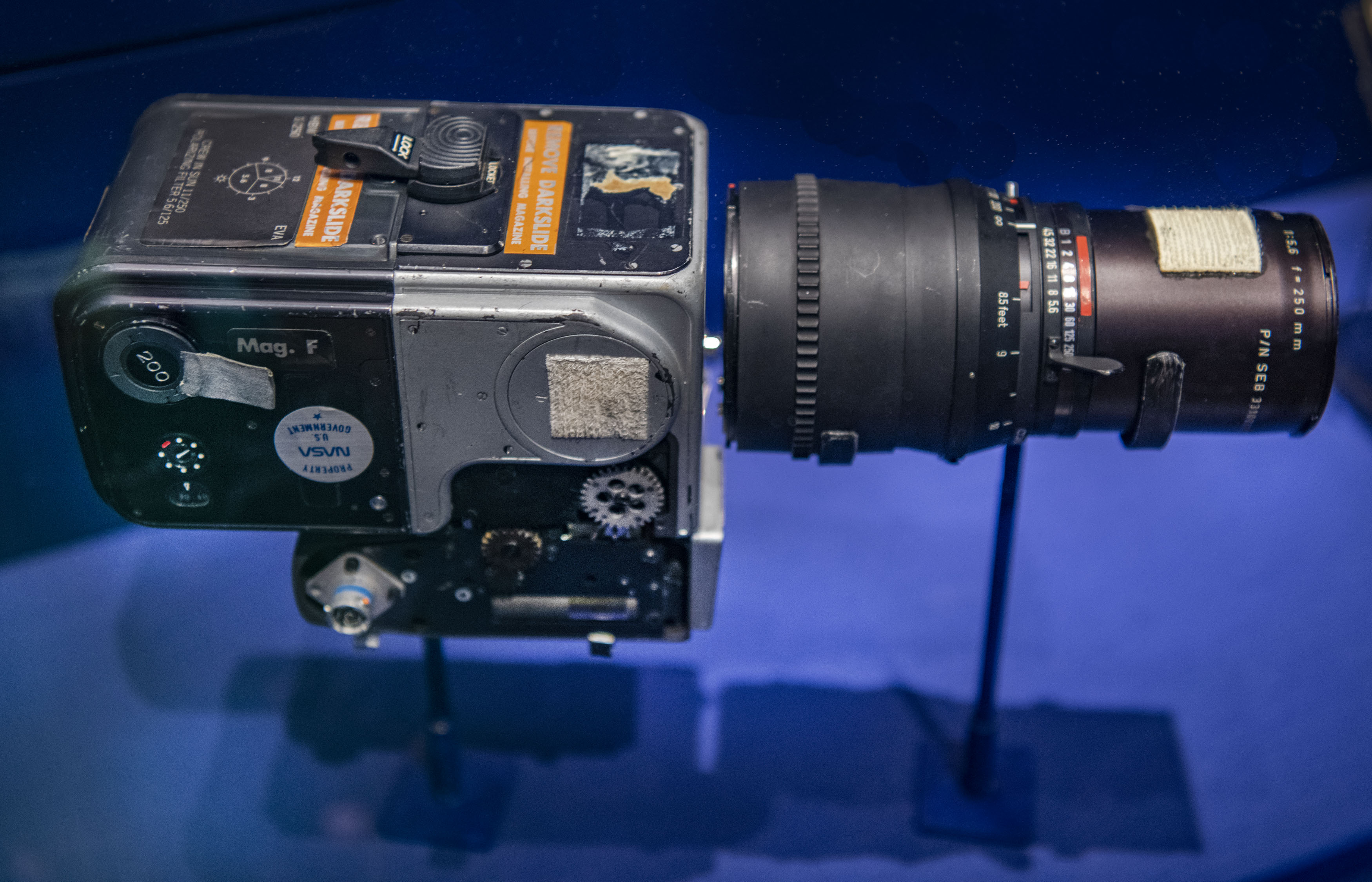 Silver Hasselblad camera body with a black 70 millimeter film magazine and a separate black telephoto lens.