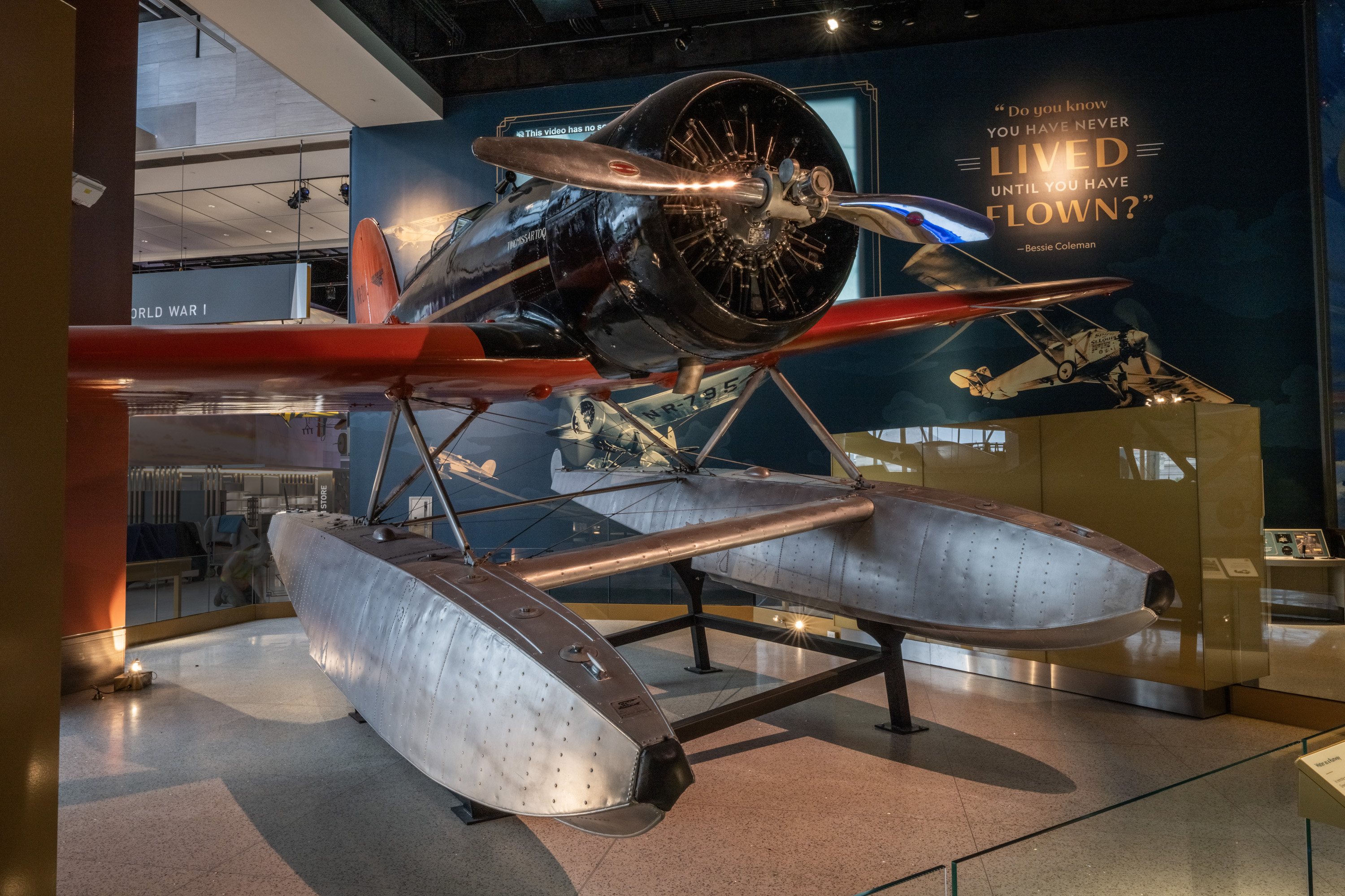 Black and red low-wing Lockheed Sirius fitted with silver pontoon floats for water landings.