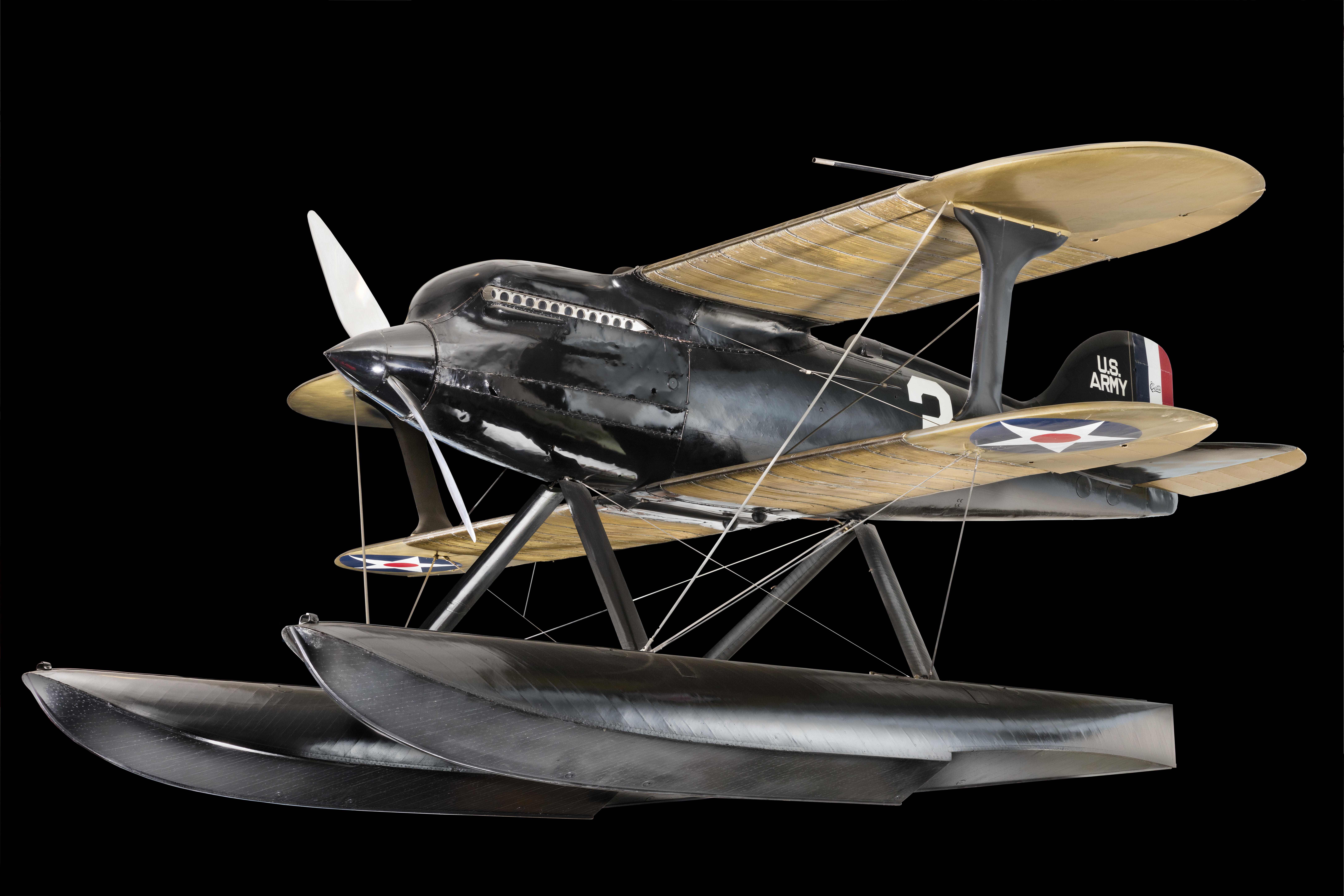 Black and gold single-seat Curtiss racing seaplane with twin floats.
