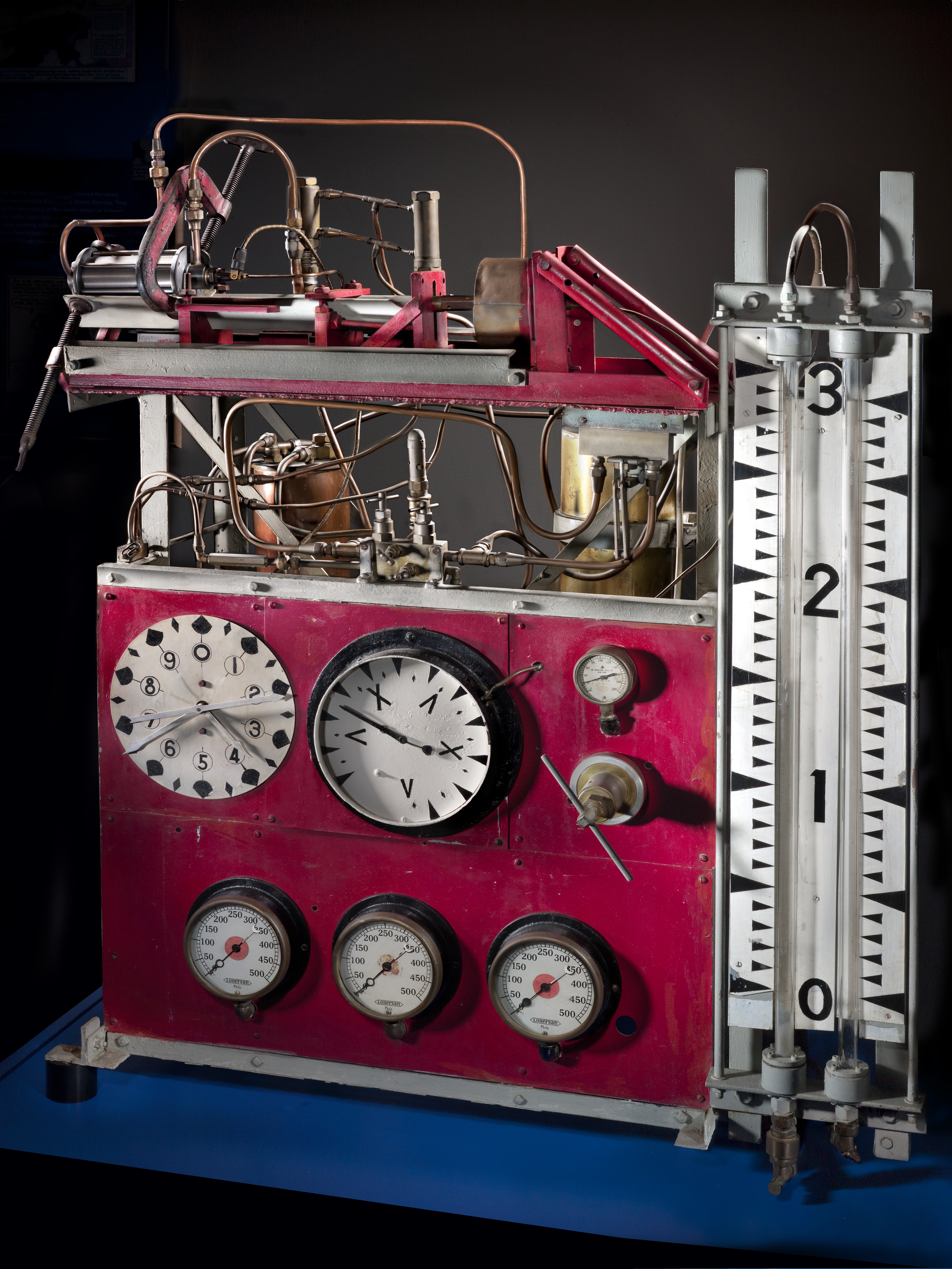 Red steel rocket test stand with fuel tanks, feed lines, gauges, and glass instrument scales.