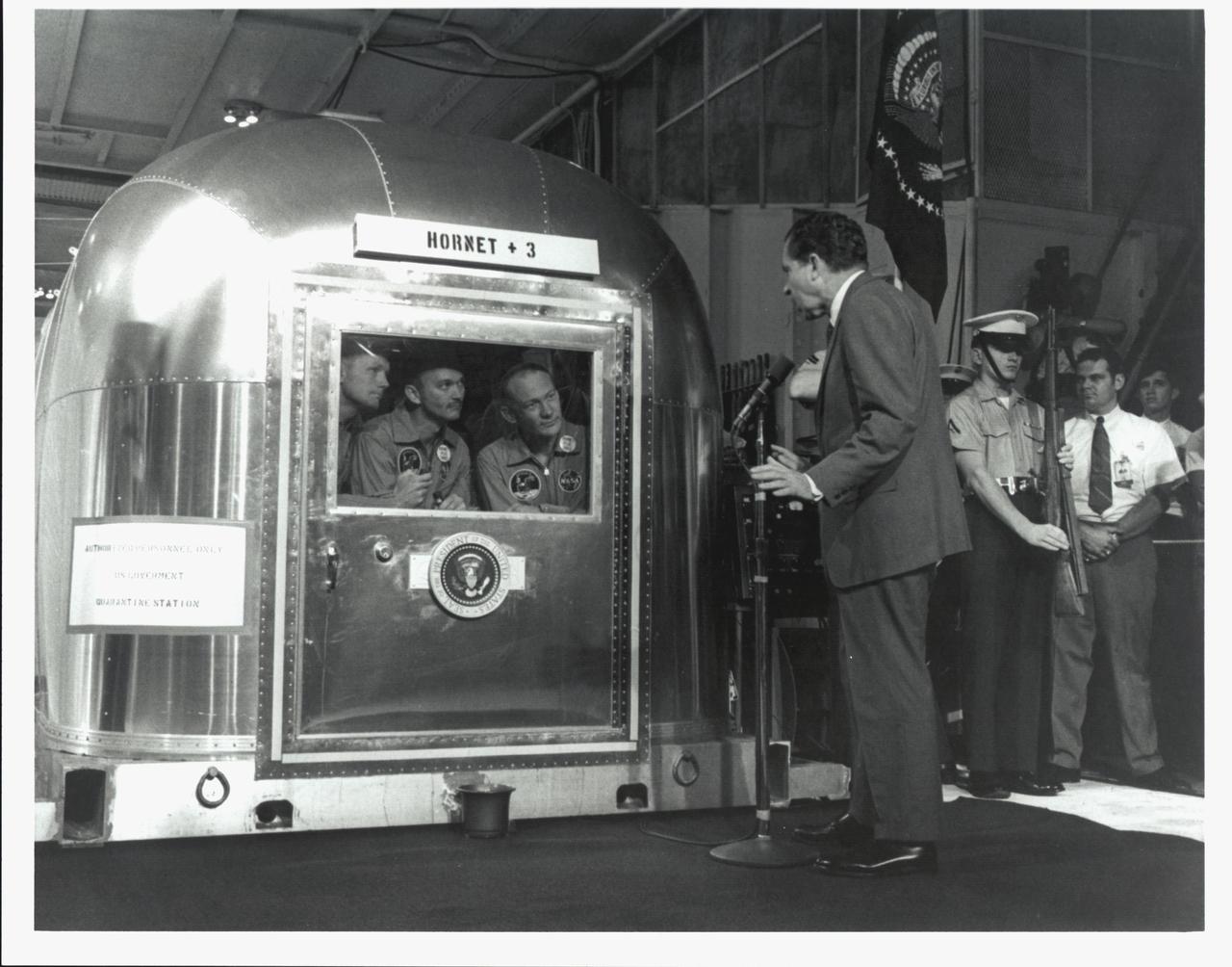 Apollo 11’s crew welcomes President Nixon from inside the quarantine facility aboard USS Hornet, July 24, 1969.