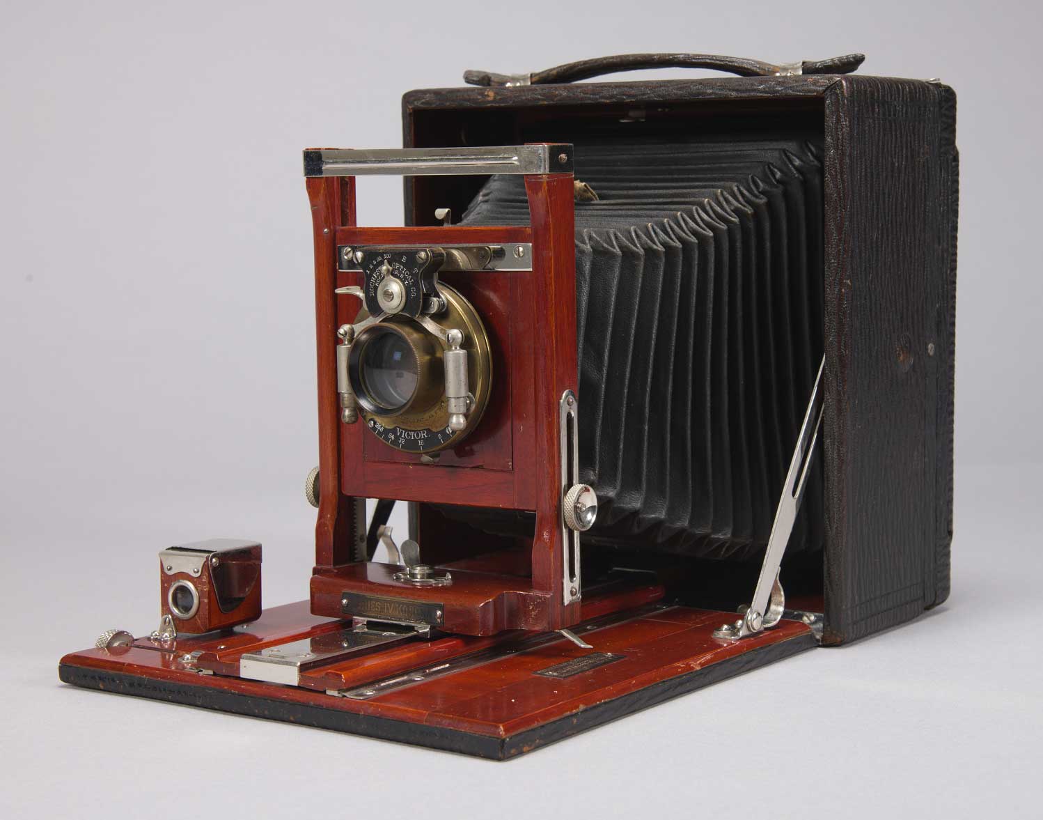Portable Korona camera in a black carrying box with a lens, folding bellows, focusing frame, compartments, and top handle.